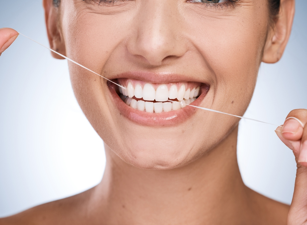 woman with white smile flossing her teeth