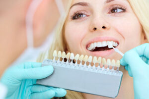 dentist checking tooth color for woman receiving dental veneers