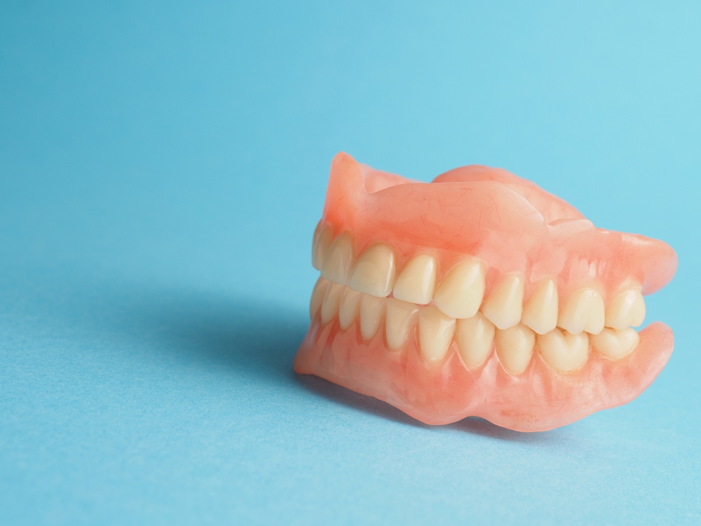 Artificial dentures on a blue background, illustrating options for replacing missing teeth, relevant to Citrus Smiles Dental Studio's denture services.