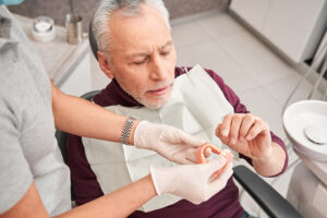 older man looking at his new dentures