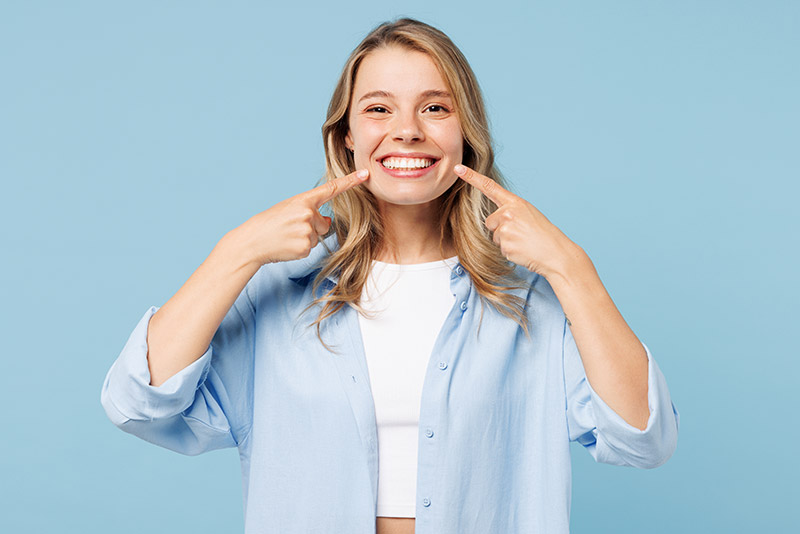 woman pointing to her healthy smile