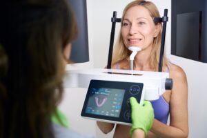 Woman undergoing dental imaging with advanced technology, displaying oral health diagnostics on a screen, emphasizing modern dental practices and patient engagement.