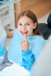 child pointing to her teeth